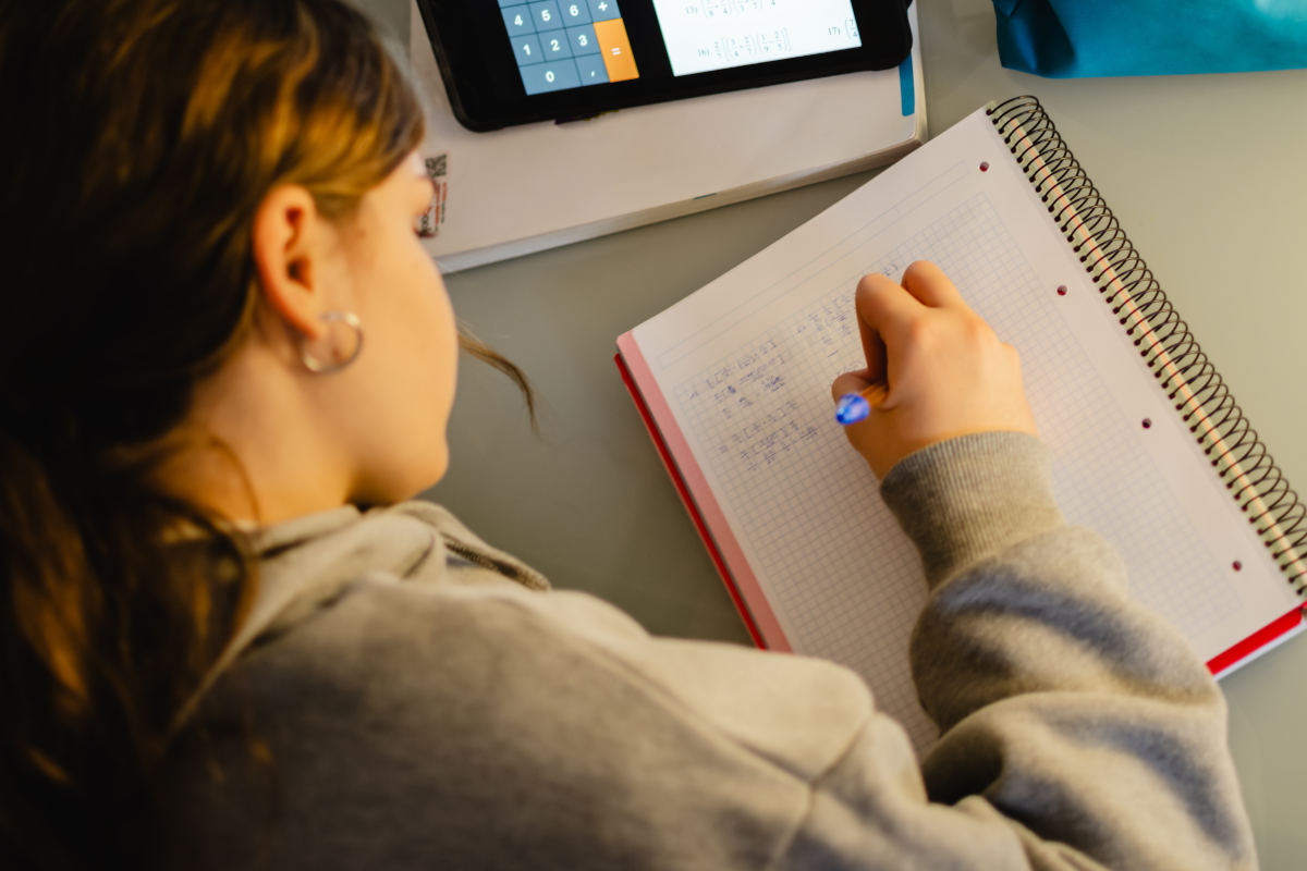 Niña hace los deberes del colegio en un cuaderno escolar