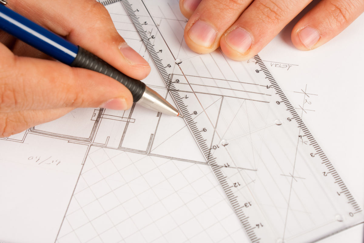 Persona trabaja en una lámina de dibujo técnico con regla y portaminas