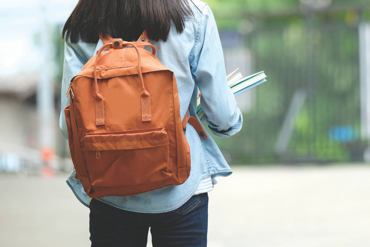 una estudiante universitaria camina a las clases con una mochila de moda a los hombros