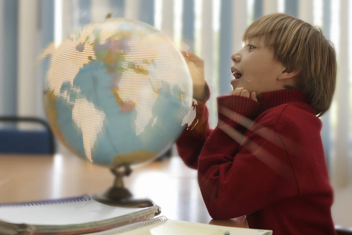 un niño toca la superficie de su globo terráqueo interactivo