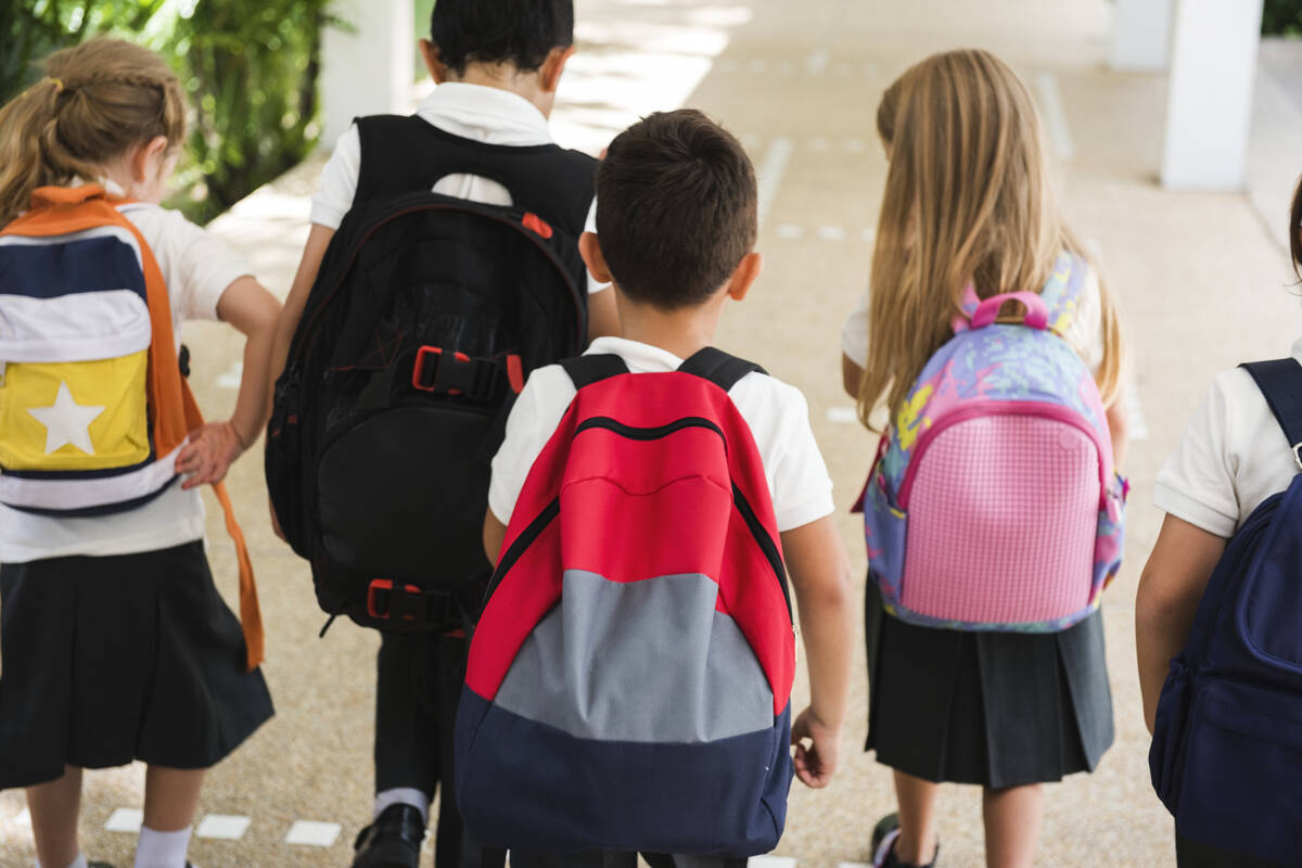 niños con mochilas van a clase